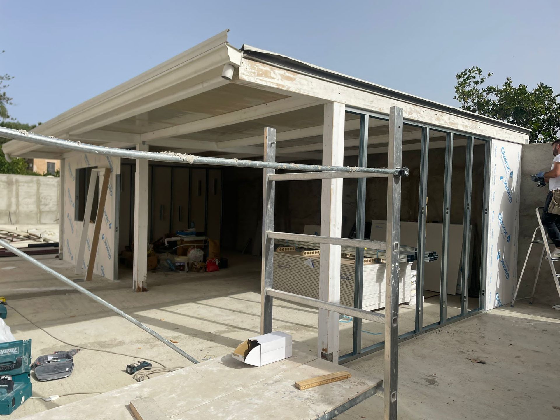 Cantiere con struttura in cemento parzialmente realizzata. Intelaiatura in acciaio visibile, cielo coperto.