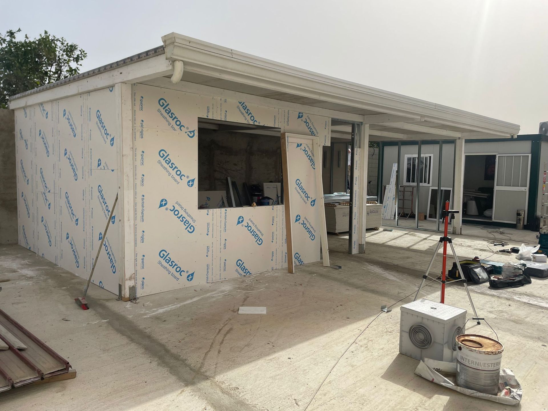 Costruzione di un edificio in corso, con pareti bianche, infissi delle finestre e fondamenta in cemento.