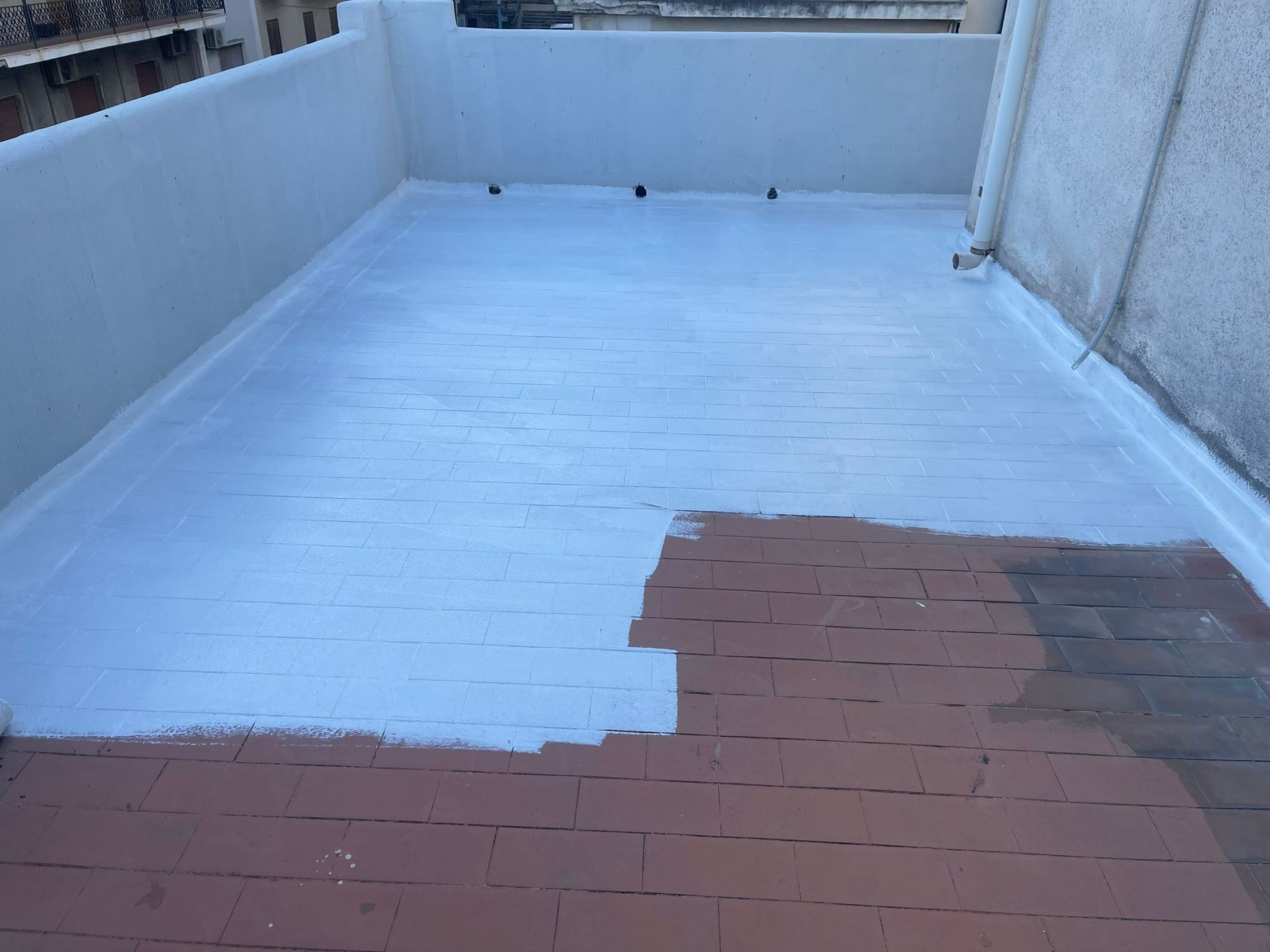 Un tetto parzialmente dipinto di azzurro chiaro su mattoni marroni. Muri grigi circondano l'area.