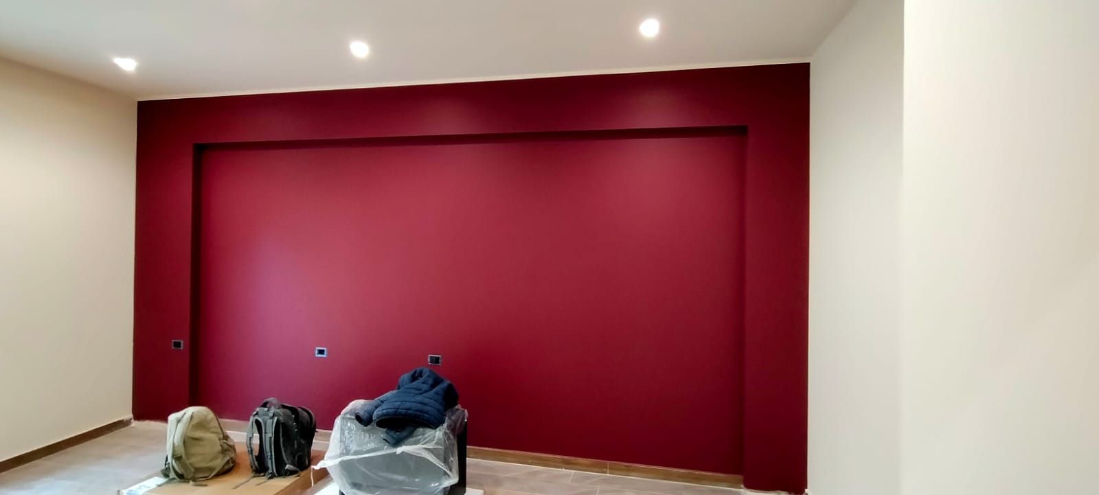 Stanza con parete decorativa rosso intenso e pareti bianche, illuminazione da incasso.