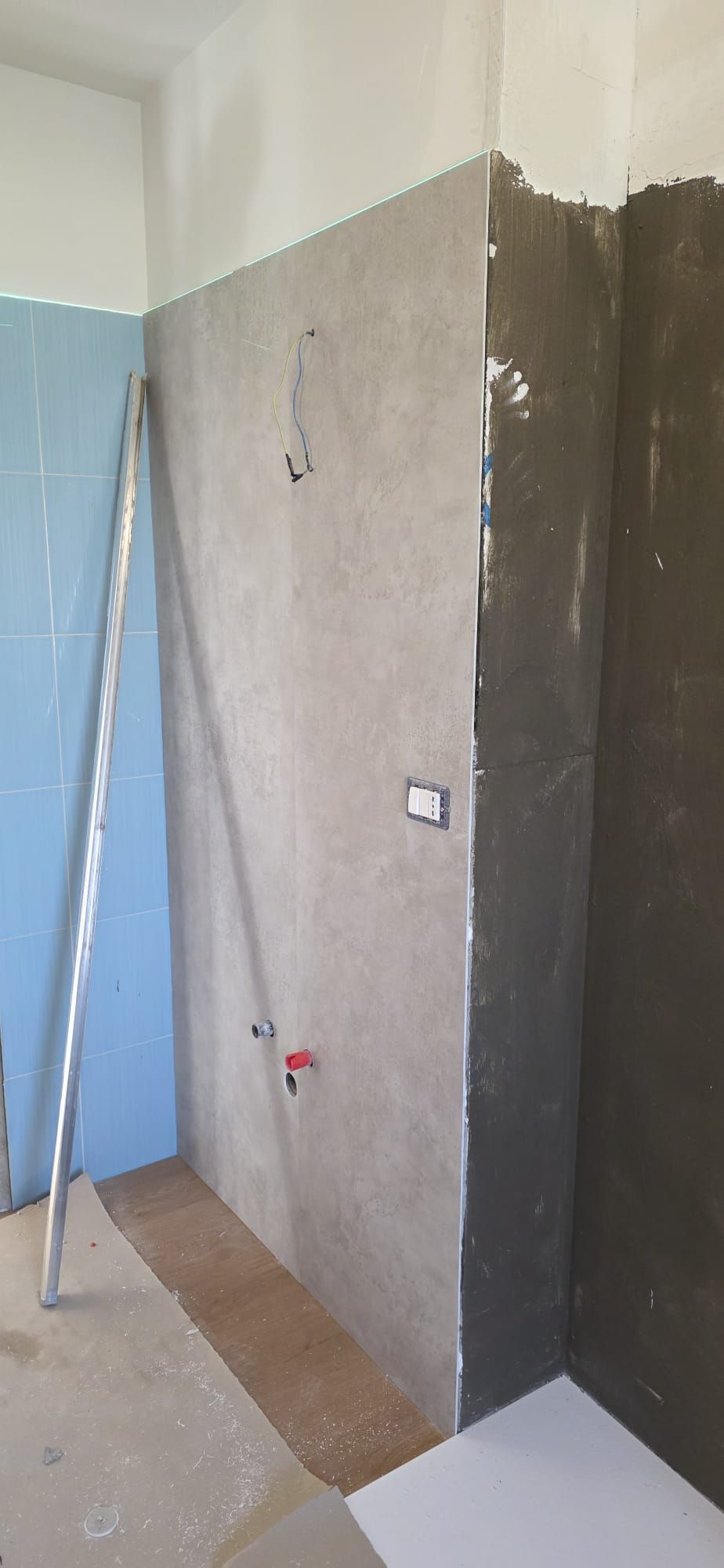 Bagno in costruzione con parete grigia, parete blu e scala metallica.