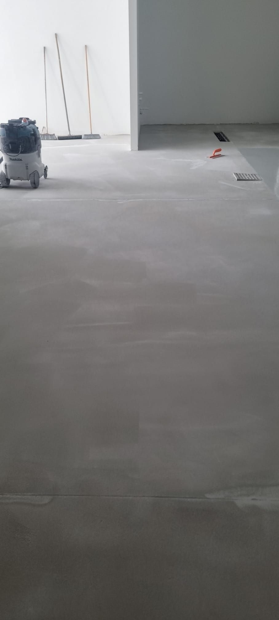 Vista interna di una stanza in costruzione con una levigatrice per pavimenti e materiali da costruzione.