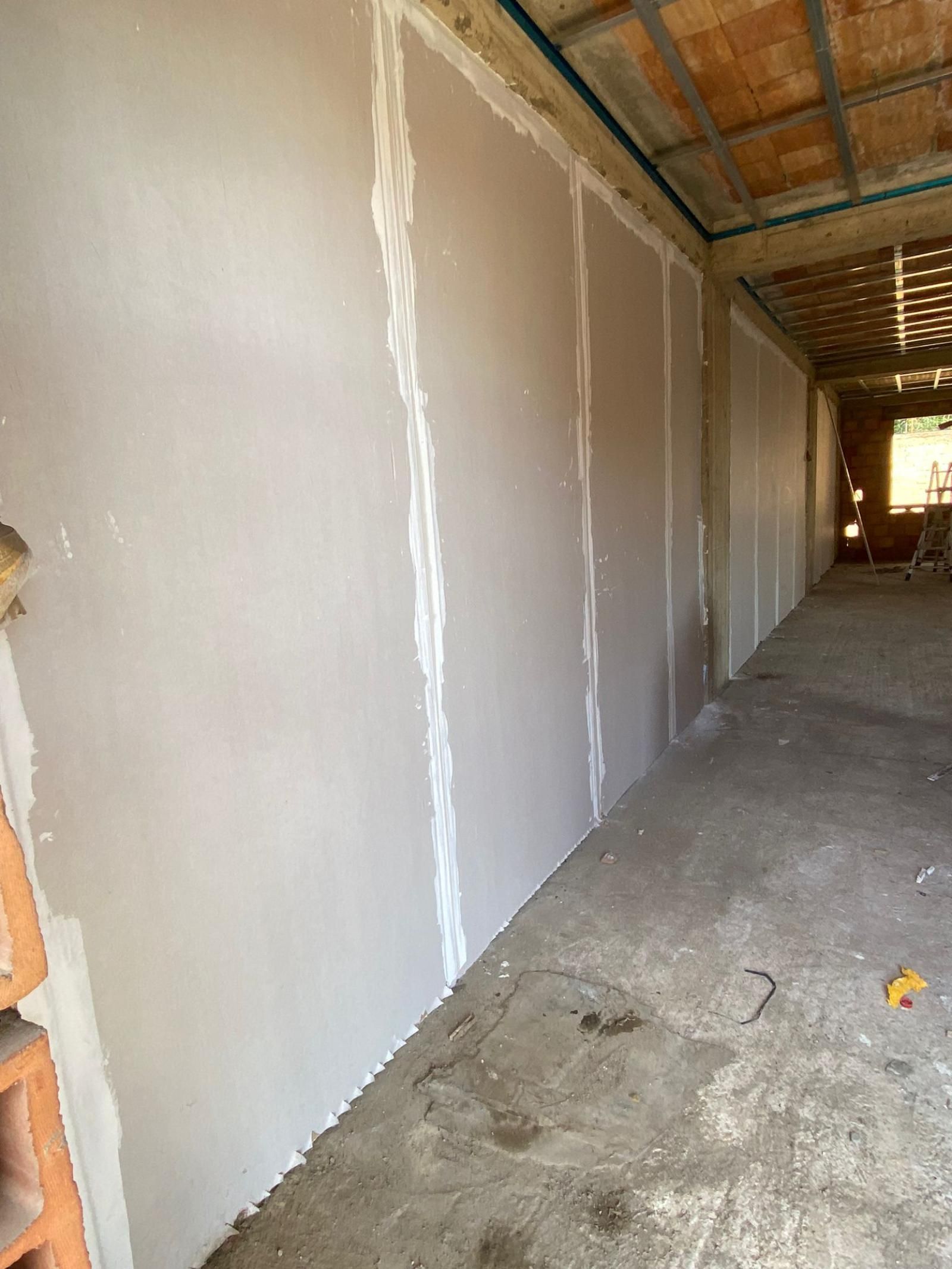 Vista interna di un cantiere. Il cartongesso è installato sulle pareti, con giunti finiti. Il soffitto e il pavimento sono grezzi.