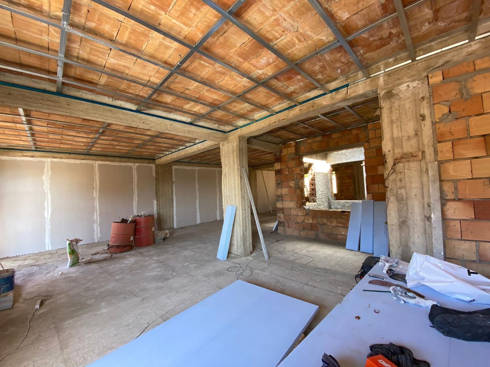 Interno di una stanza in costruzione, con mattoni a vista, cartongesso e struttura metallica.