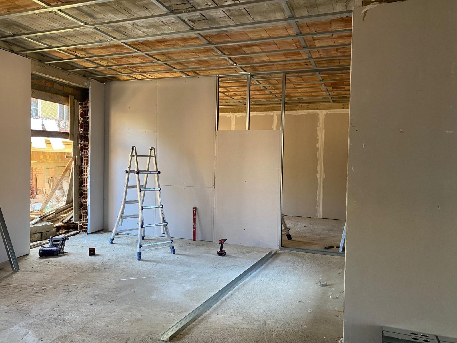 Interno di una stanza in costruzione con cartongesso e struttura del soffitto a vista.