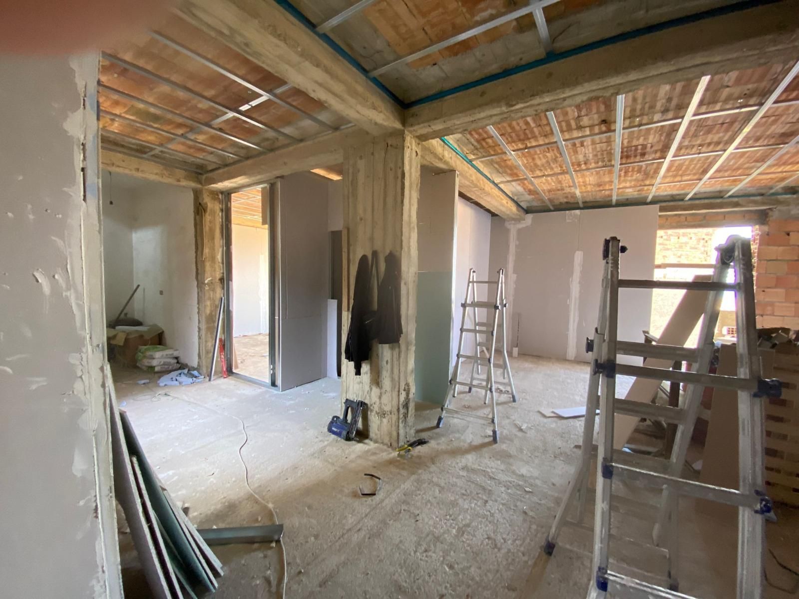 Cantiere interno con soffitto a vista, cartongesso e scale.