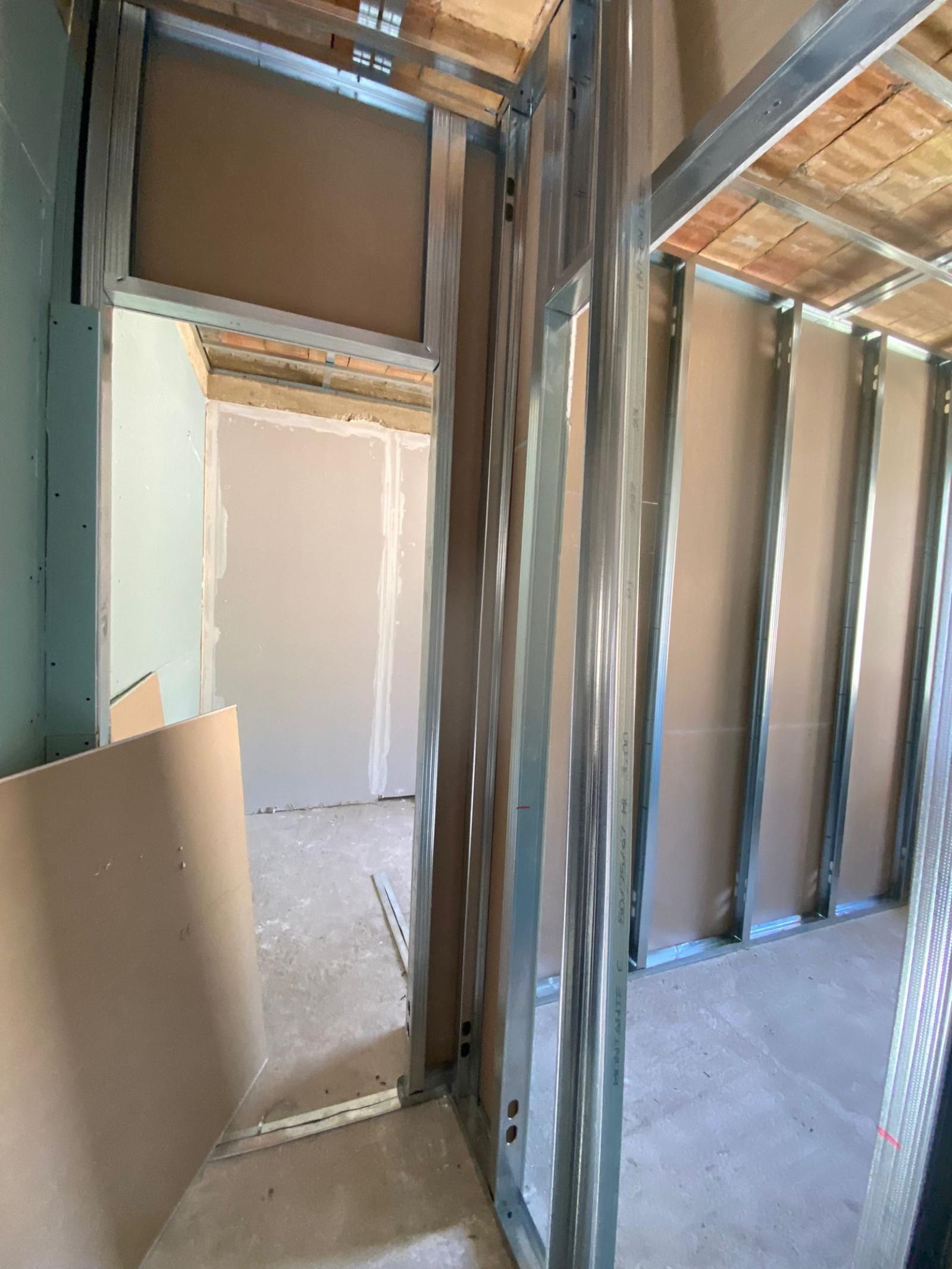 Struttura interna di una stanza con installazione di cartongesso in corso. Montanti metallici e struttura del soffitto a vista.