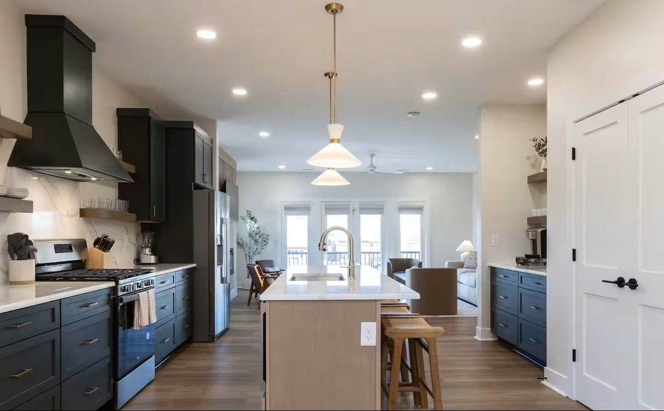 Modern kitchen with dark cabinets, white countertops, and a central island with stools.