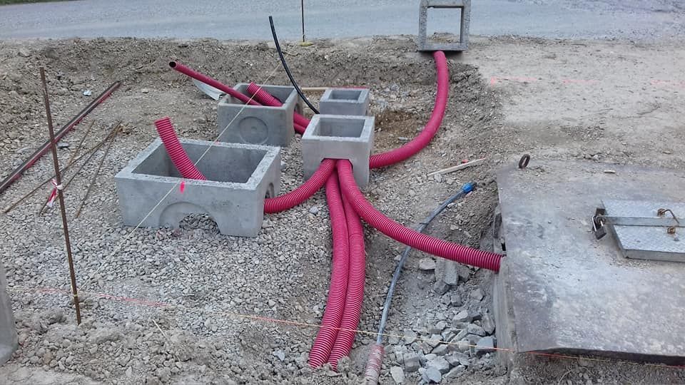 Scatole di cemento per servizi pubblici con tubi rosa acceso che attraversano un cantiere ghiaioso.