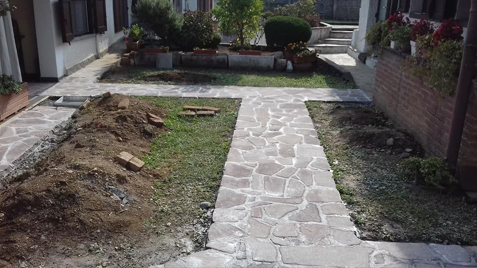 Sentiero in pietra tra gli edifici residenziali, con terra smossa sul lato sinistro.