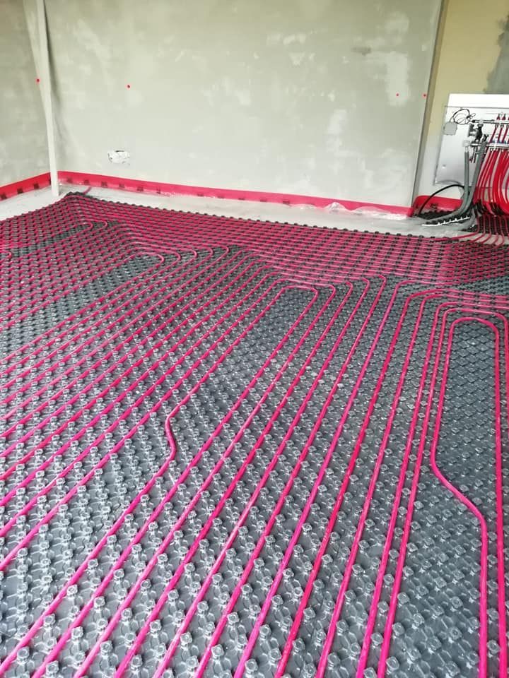 Il pavimento interno della stanza era ricoperto da tubi di riscaldamento a pavimento rosa e neri prima dell'installazione.