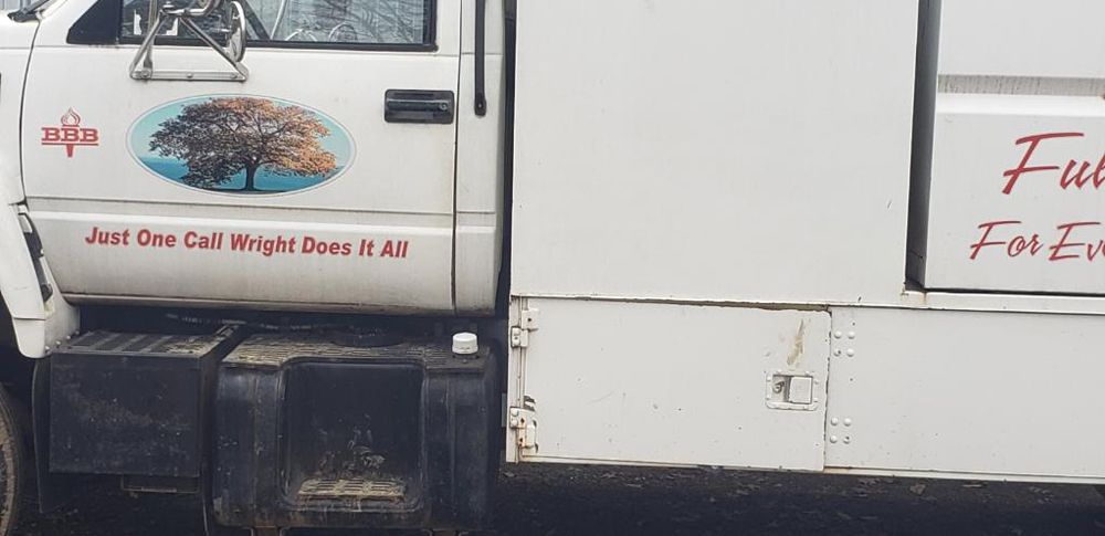 A white truck with a tree on the side is parked on the side of the road.