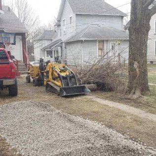 A yellow tractor is parked in a driveway next to a house.
