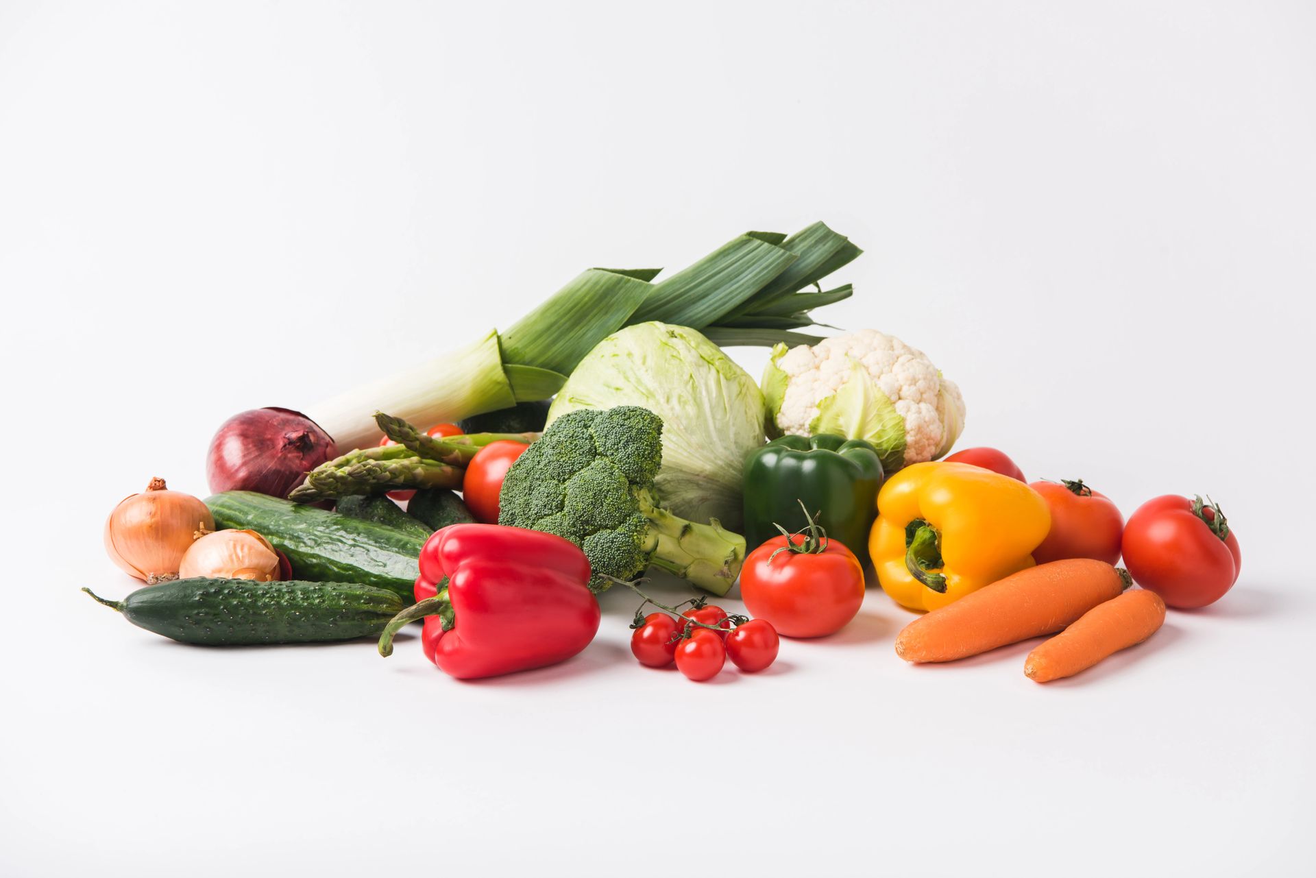 Un mucchio di verdure fresche e colorate: pomodori, peperoni, broccoli, carote, cipolle, cetrioli, porri, cavolfiori e cavoli.