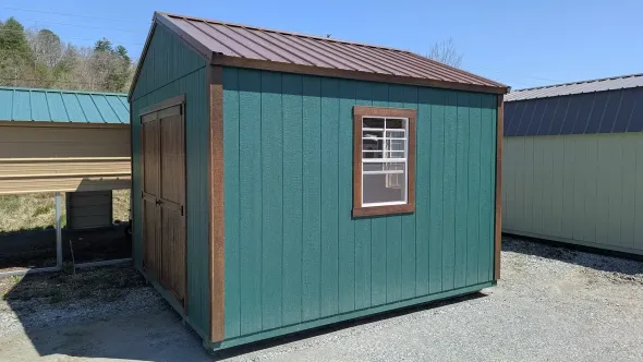 Green shed with brown trim and a brown metal roof, against a blue sky.