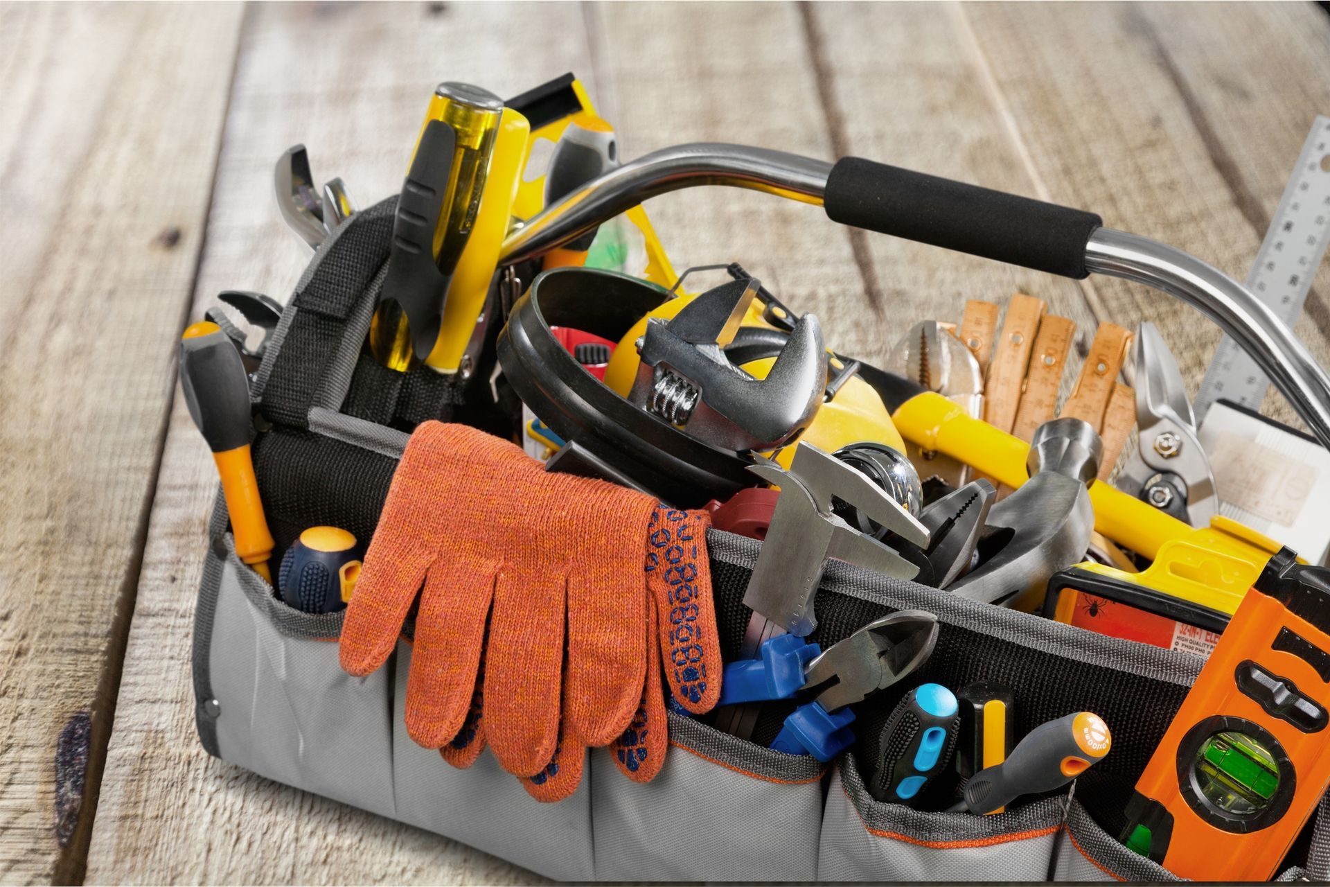A toolbox filled with tools and gloves on a wooden table.