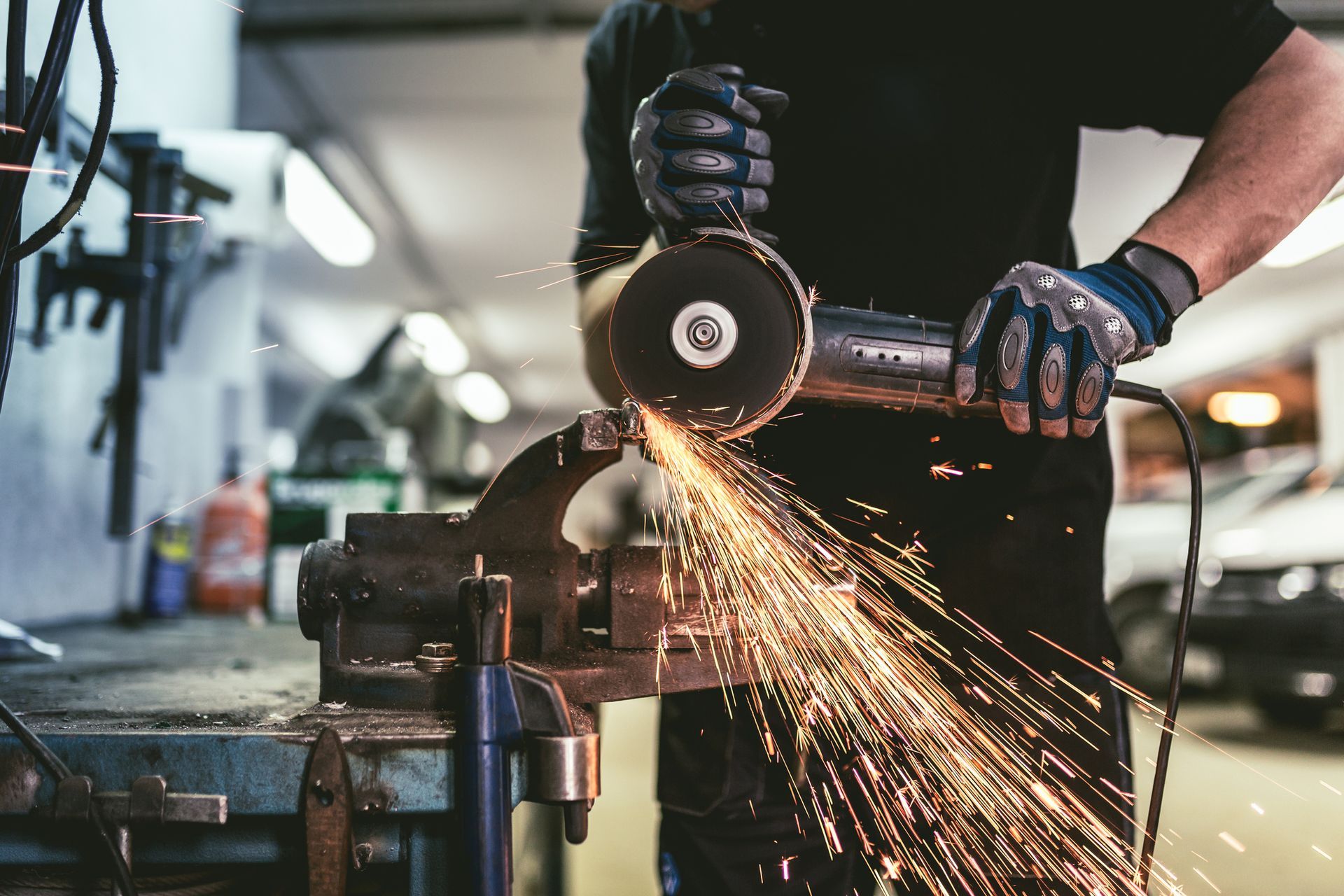 A man is using a grinder to cut a piece of metal.