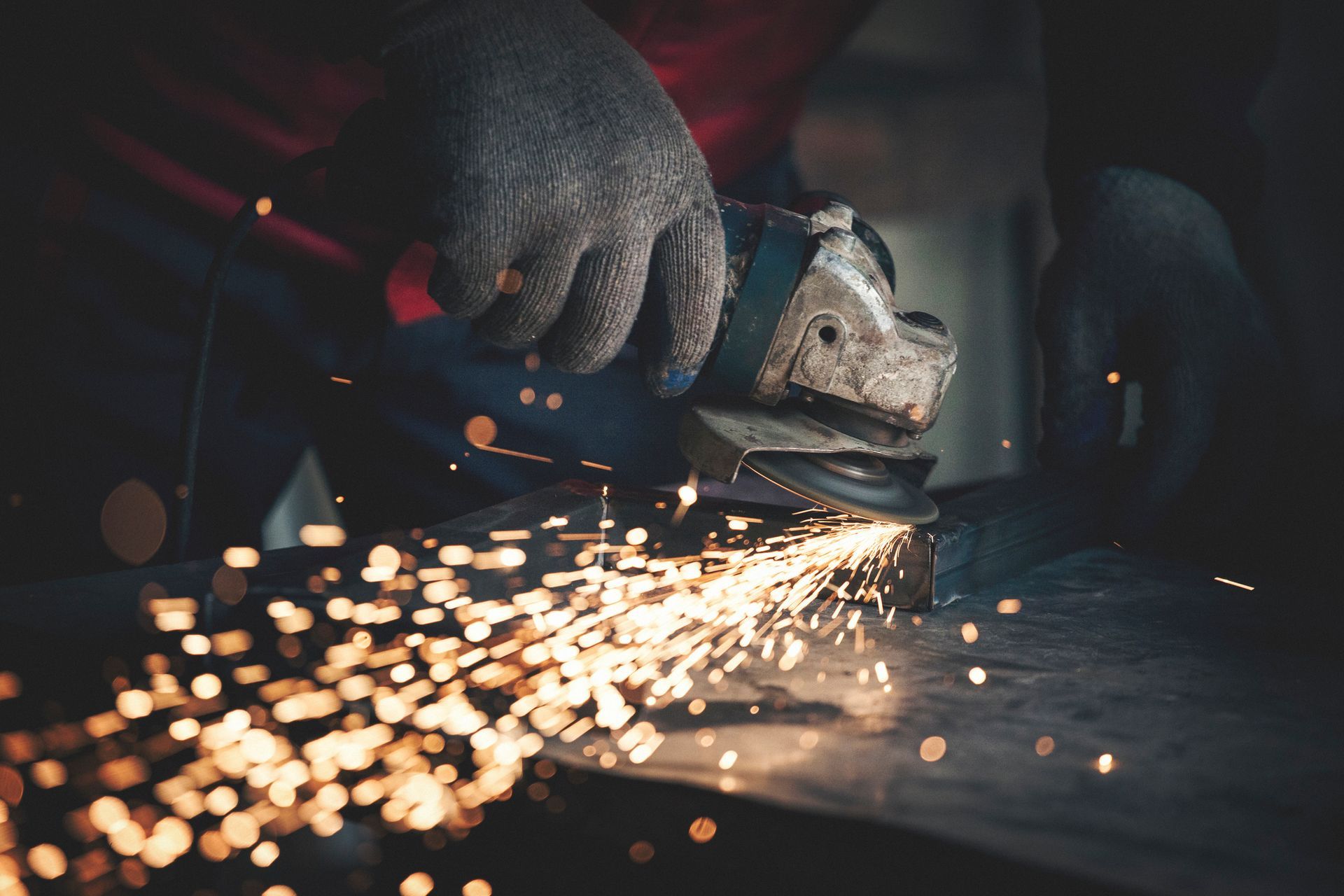 A person is grinding a piece of metal with a grinder.