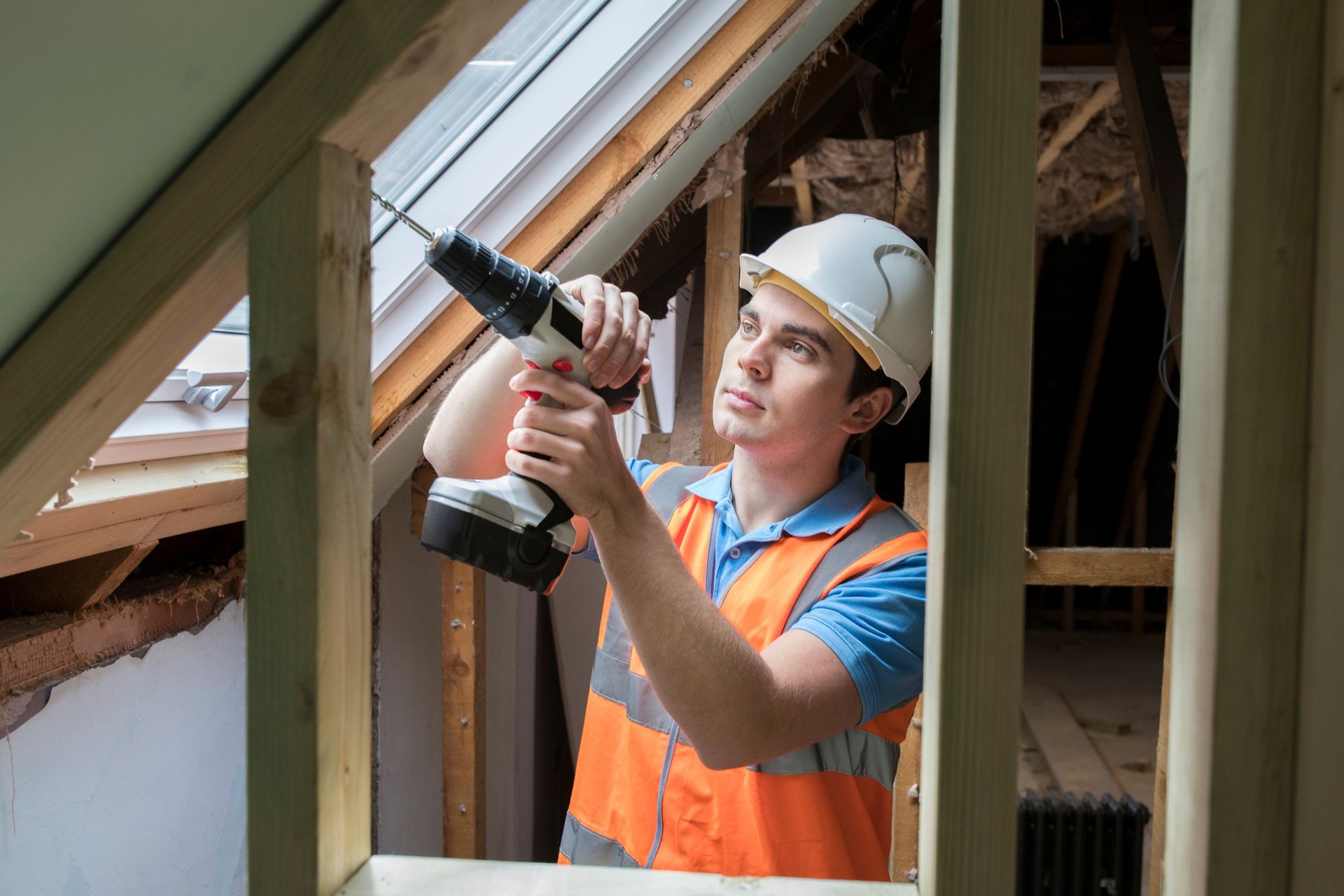 A man is using a drill to fix a window in a building.