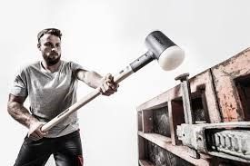 A man is holding a large rubber mallet in his hands.