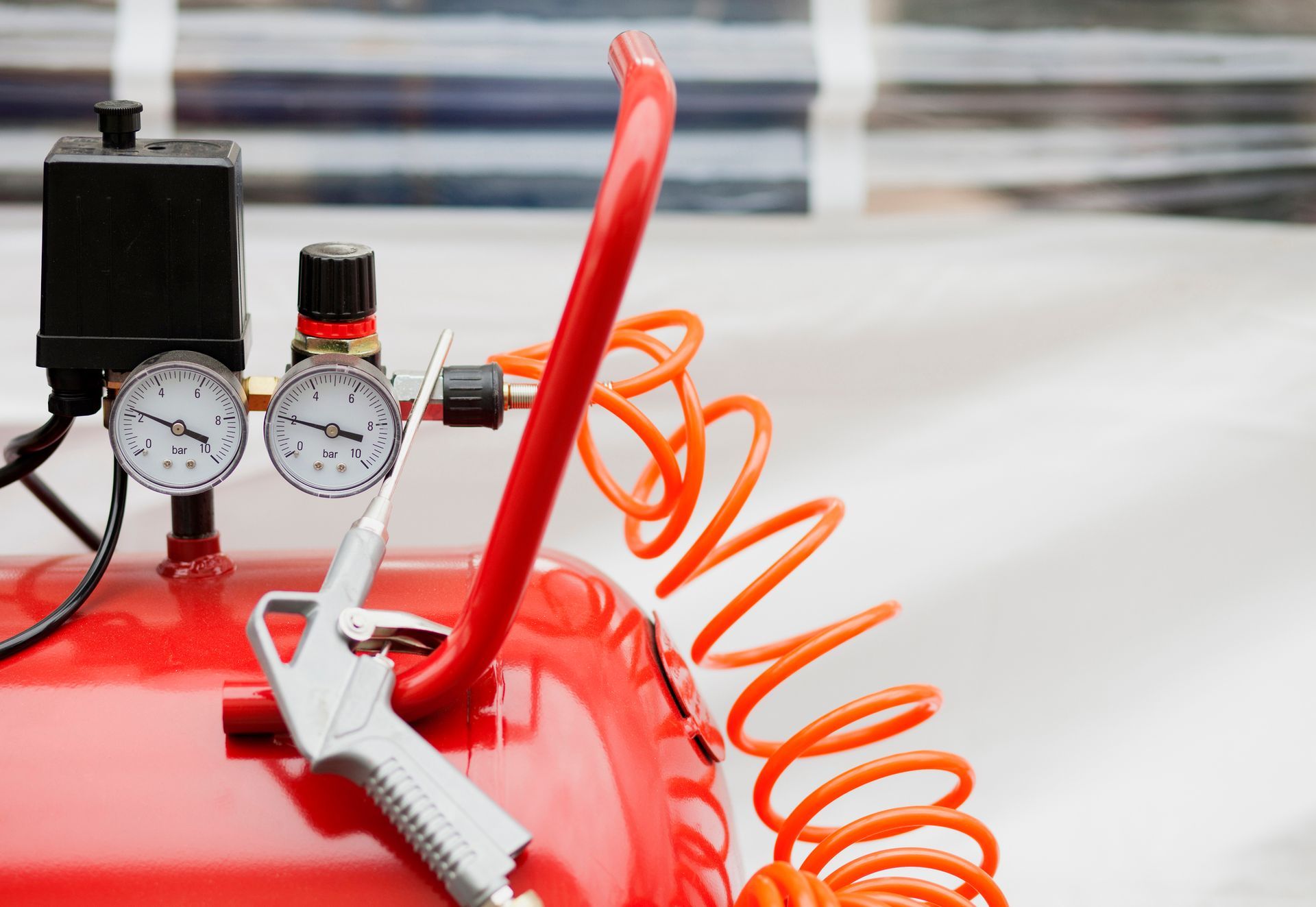 A red air compressor with a hose attached to it.