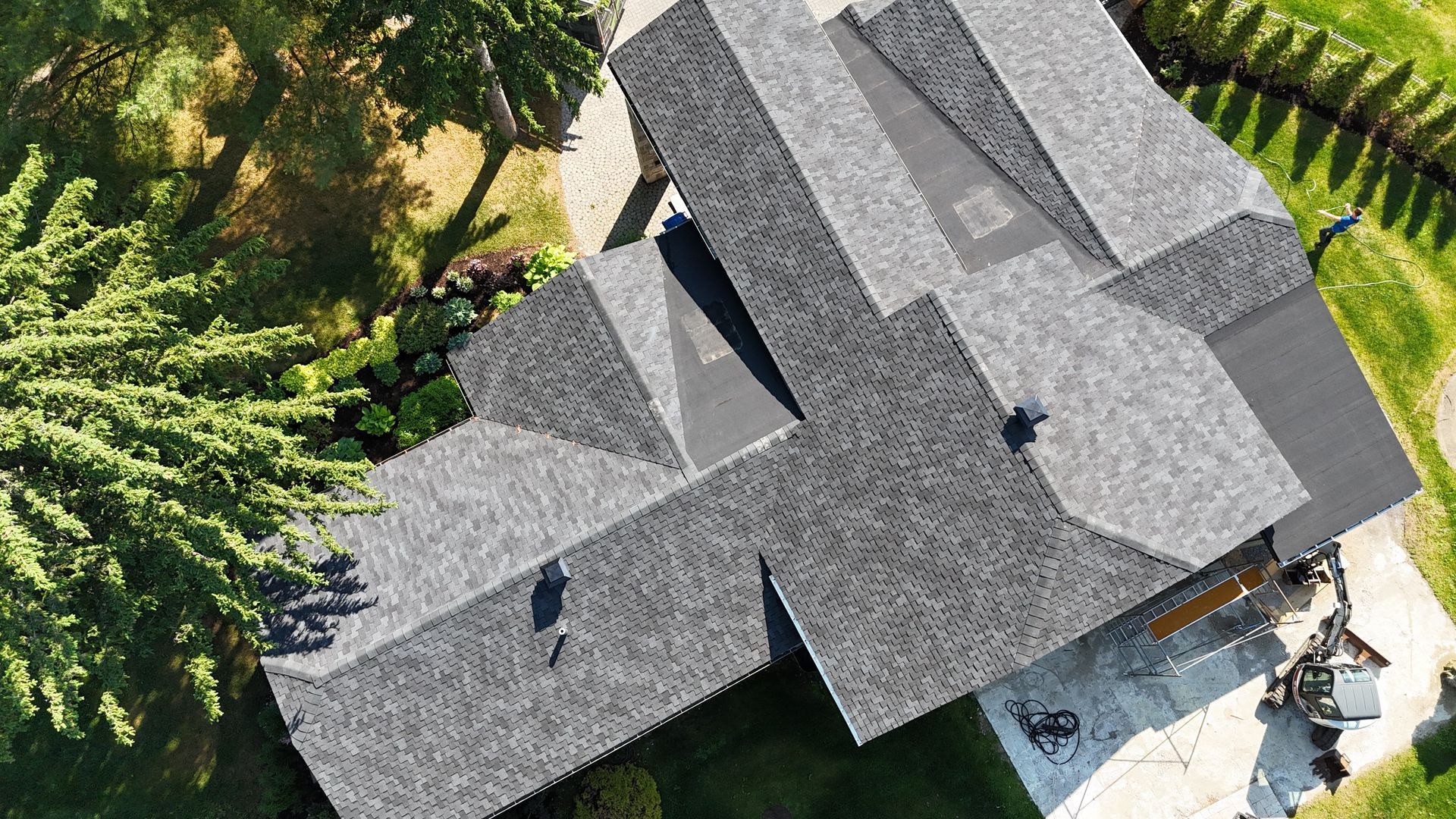 Une vue aérienne d'une maison au toit gris entourée d'arbres.