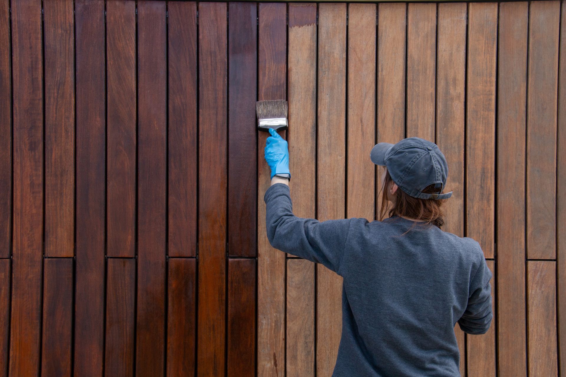 Un homme peint un mur en bois avec un pinceau.