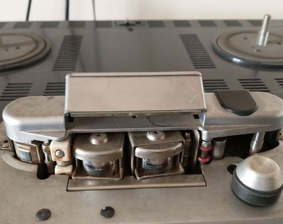 Close-up of a vintage reel-to-reel tape recorder's heads and mechanisms. Silver and gray tones.
