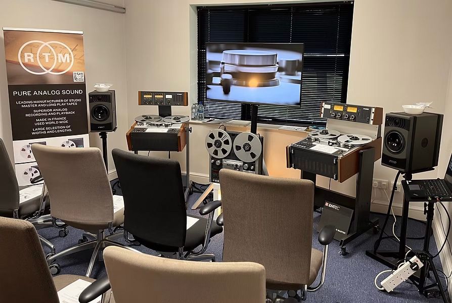 Room with audio equipment, reel-to-reel tape decks, speakers, and chairs set up for listening.