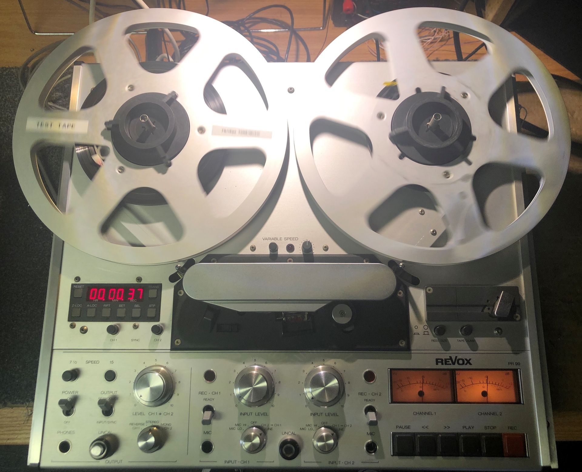 Reel-to-reel tape recorder with two silver reels. A digital counter displays red numbers.