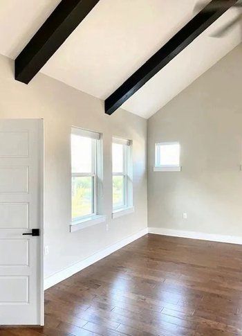 A large empty room with hardwood floors and a vaulted ceiling.