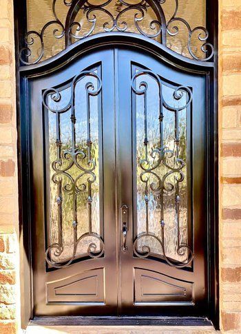 A black wrought iron door is on a brick wall.