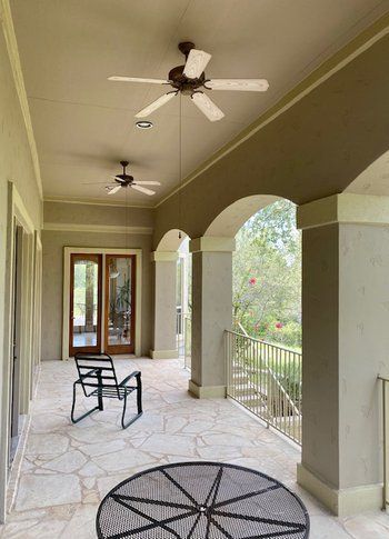 A porch with a table and chairs and a ceiling fan