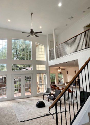 A living room with a lot of windows and a staircase leading to the second floor.