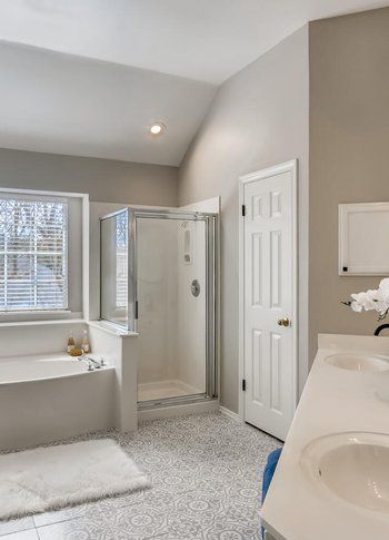 A bathroom with a sink , tub , shower and window.