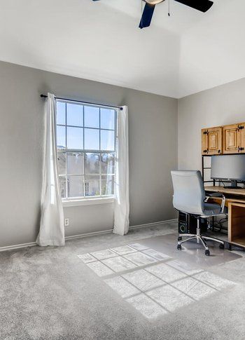 A room with a desk , chair , computer and window.
