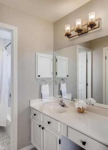 A bathroom with a sink , mirror and light fixture.