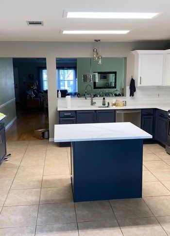 A kitchen with a large blue island in the middle of it.