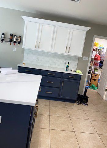 A kitchen with blue cabinets and white counter tops.