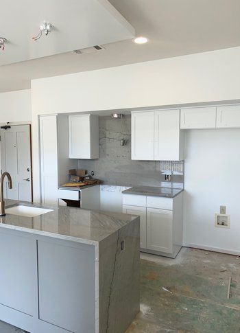 A kitchen with white cabinets and a large island.