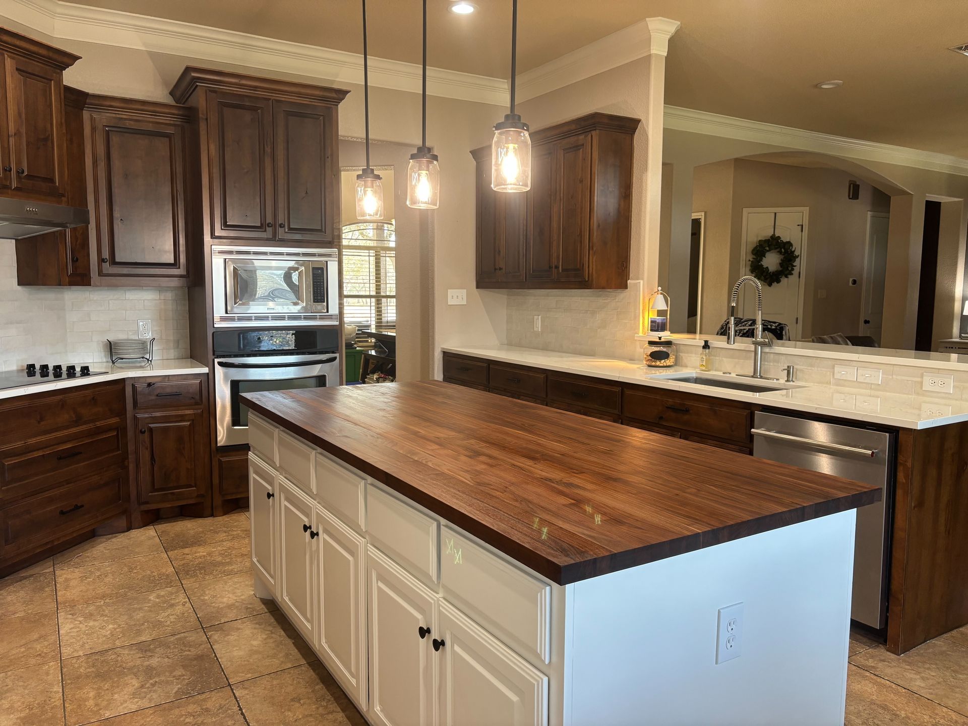 Kitchen remodel featuring stained cabinets painted island butcher block countertop and quartz countertops in Liberty Hill