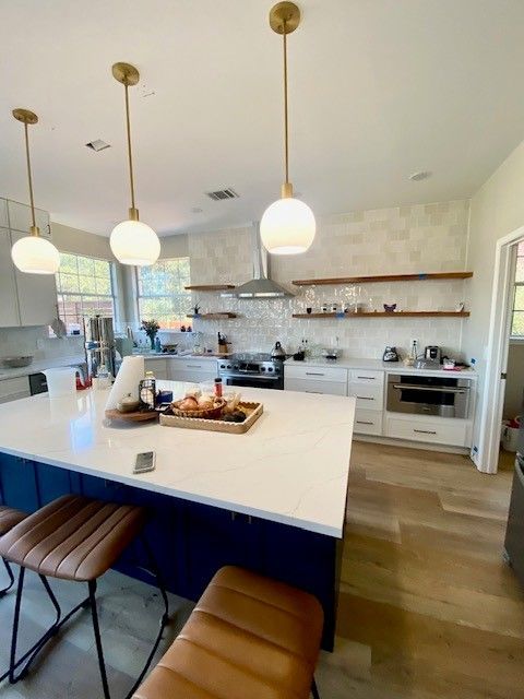 Modern kitchen remodel in Austin, TX featuring navy blue island cabinets, white quartz countertops, 