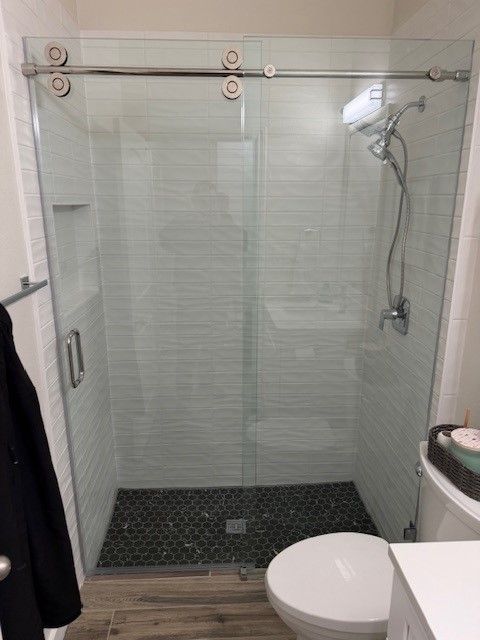 after photo of West Austin bathroom remodel with custom tile wall niche and frameless sliding glass 