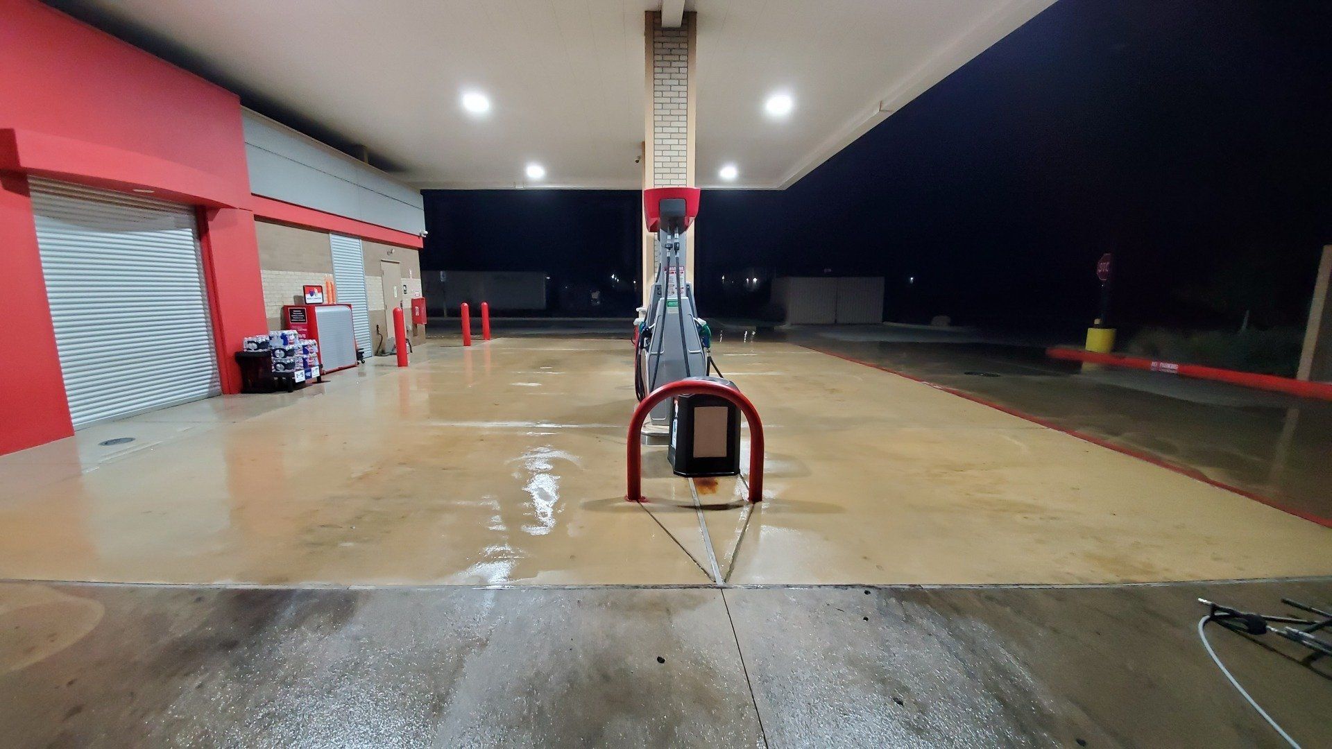 an empty gas station at night with a red and white building .