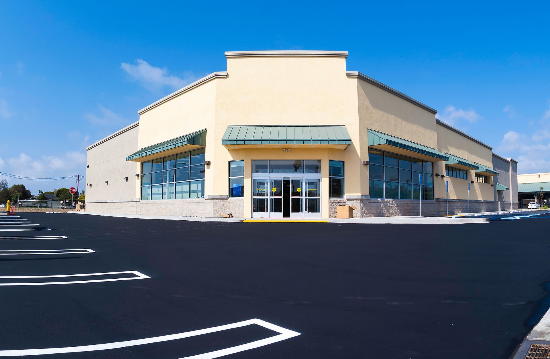 Empty commercial building with parking lot under a bright blue sky.