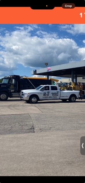 Construction worker in blue hard hat inspects freshly paved asphalt road.