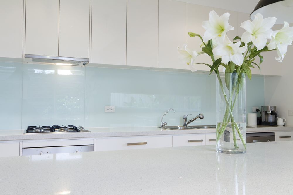 A Kitchen With White Cabinets And A Vase Of Flowers On The Counter — Nobbs & Myers Glass In Mullumbimby, NSW