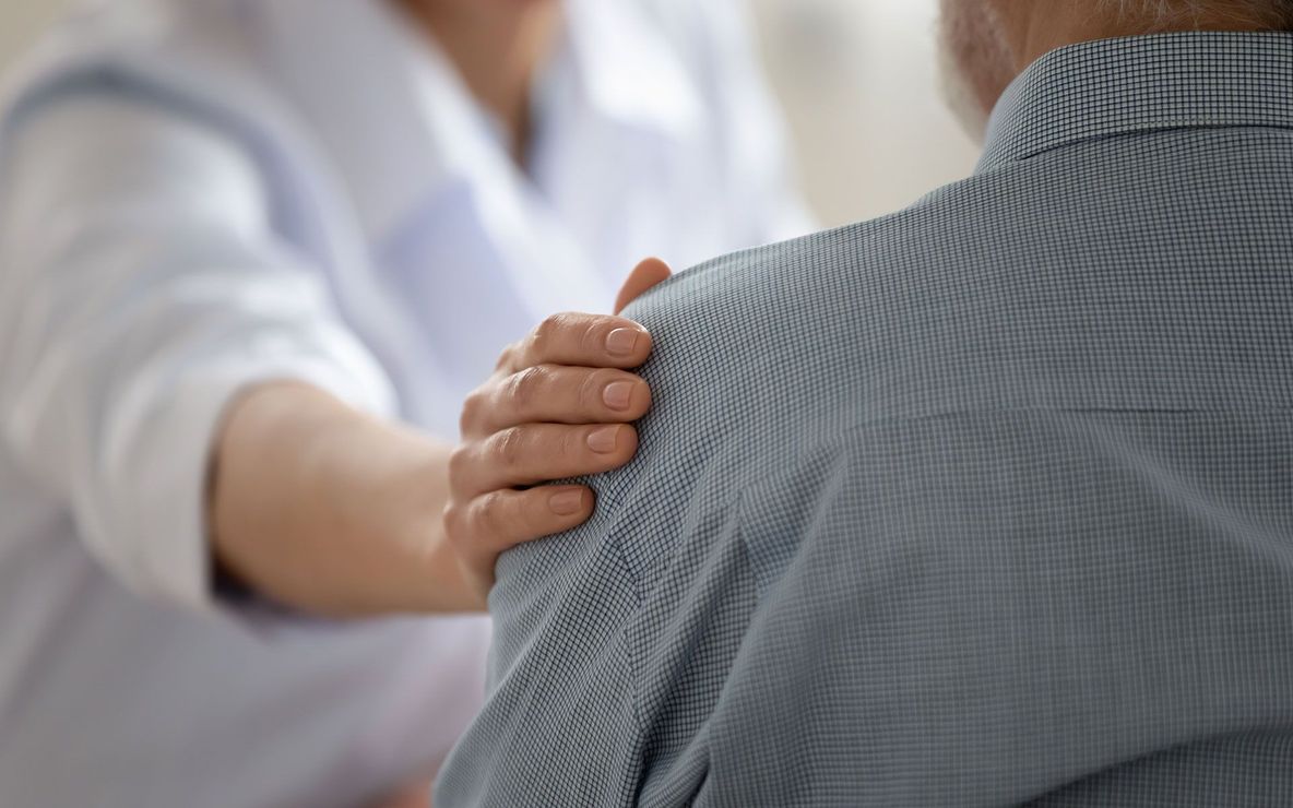 Person with hand on shoulder, showing care and comfort.