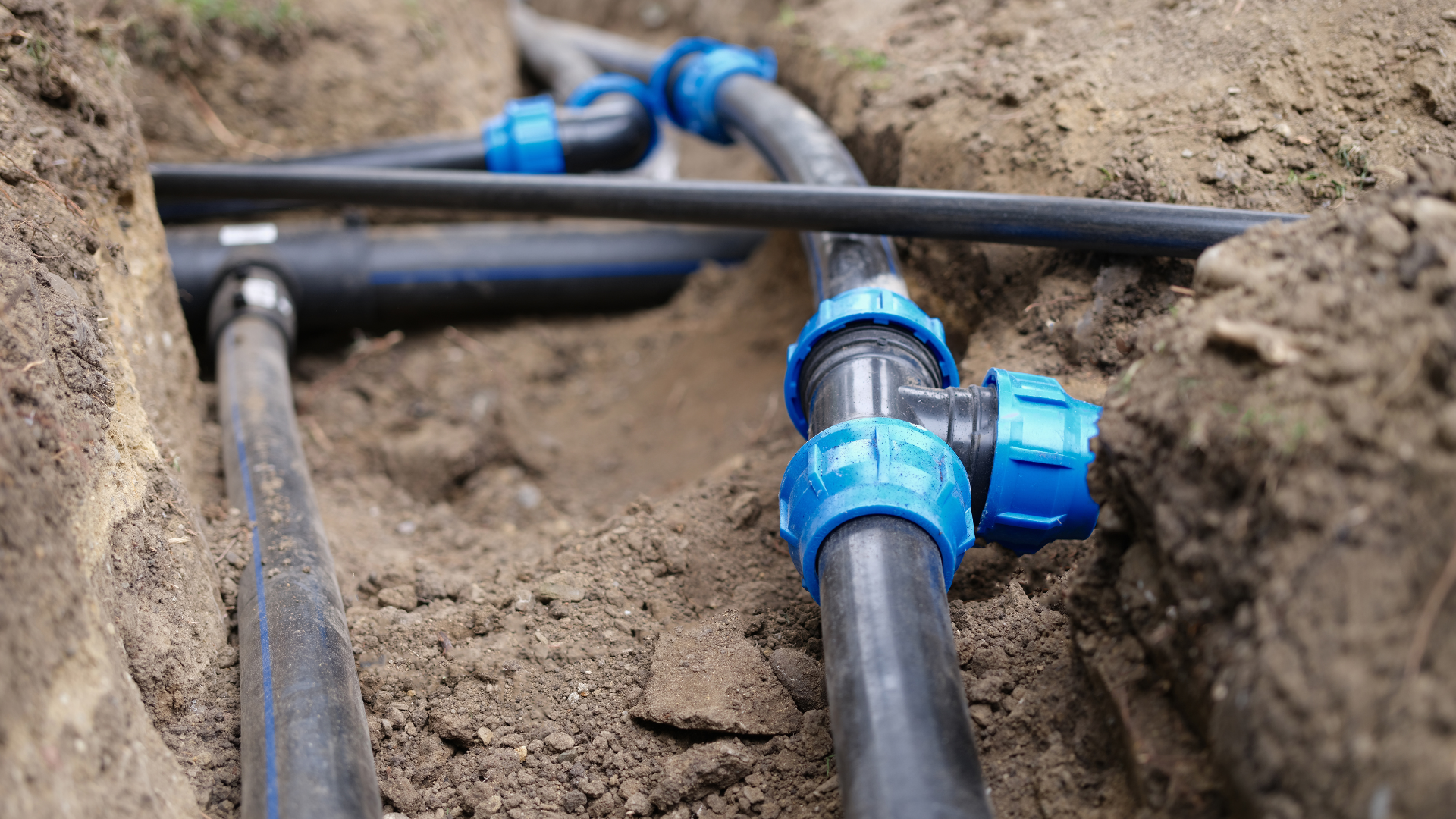 A man is fixing a hose in the dirt.