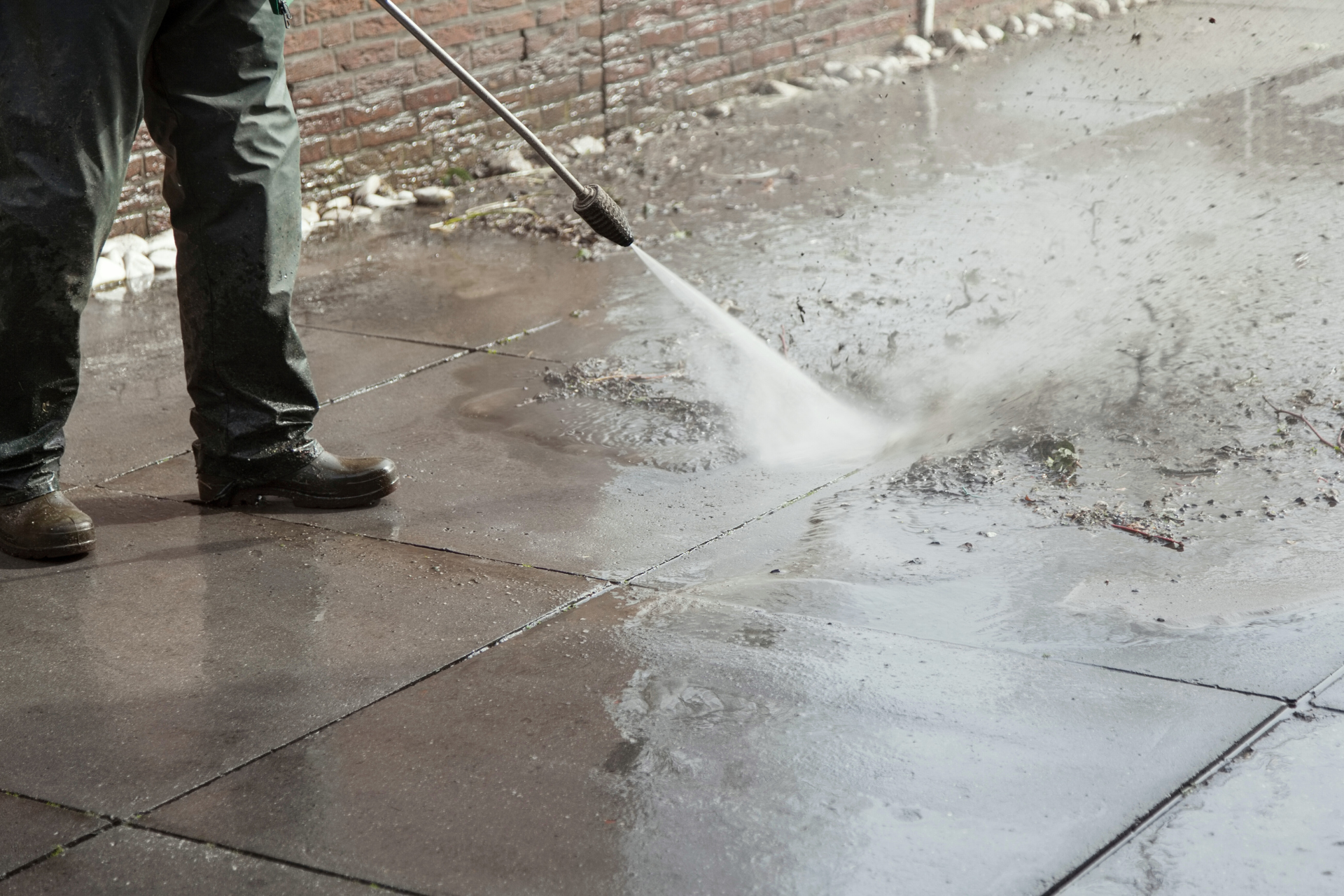 A person is using a pressure washer to clean a concrete floor.